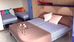 Una habitación con dos camas, una más grande y otra más pequeña, con cabecero de madera y estante superior.