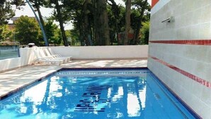 Una piscina con agua azul cristalina, rodeada por un muro de baldosas blancas con rayas rojas.