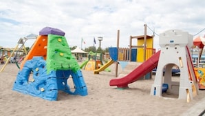 A playground with various play structures including a slide, climbing area, and a castle-like playhouse.