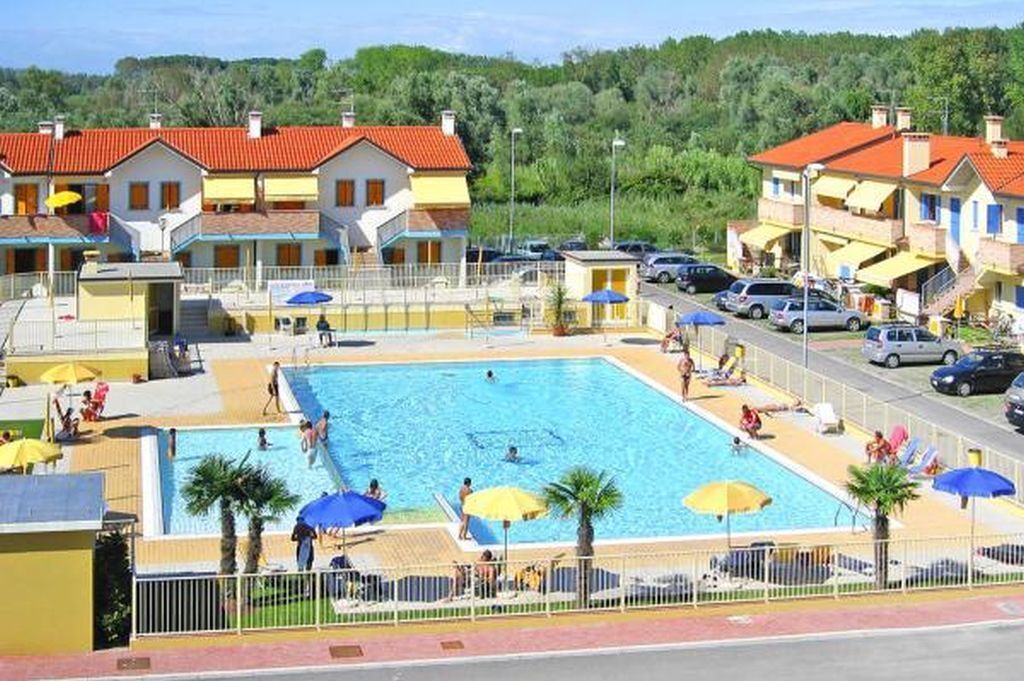 Un espace piscine comprenant plusieurs bassins, des chaises longues et des parasols.