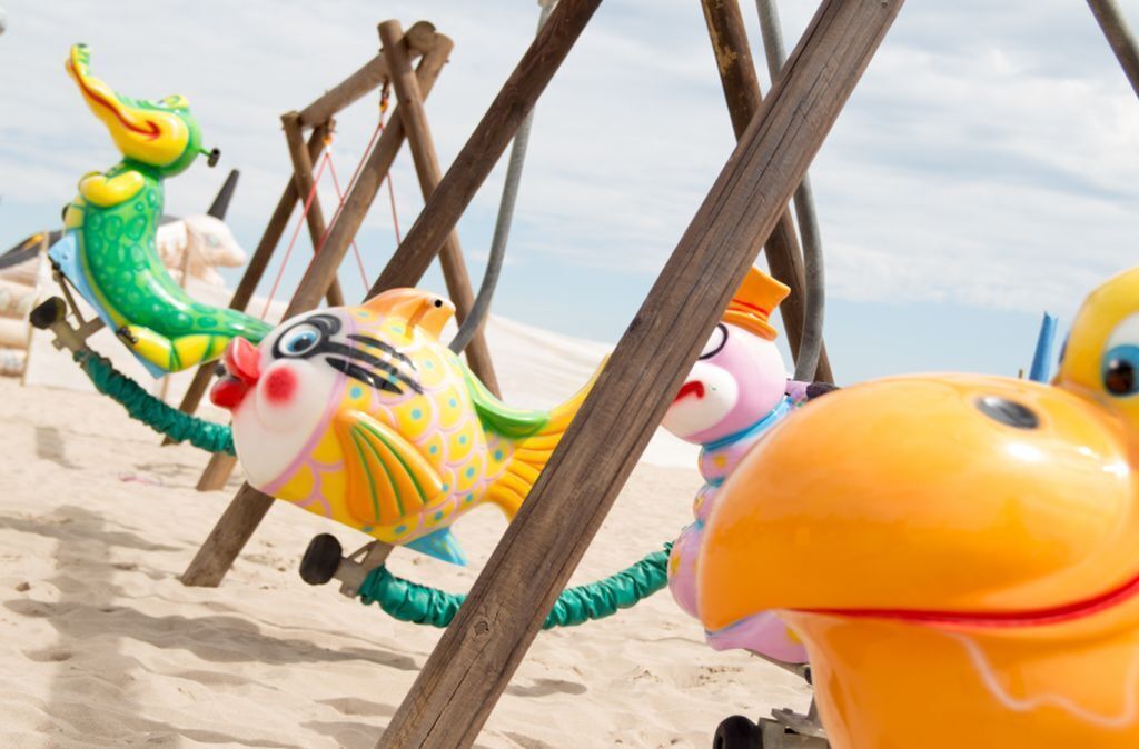 Een strand met kleurrijk speelgoed en houten constructies.