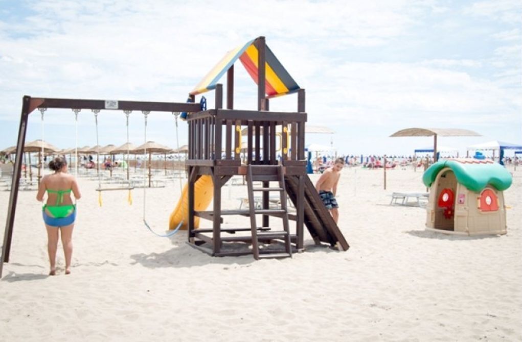Een strand speeltuin met een glijbaan en schommels.