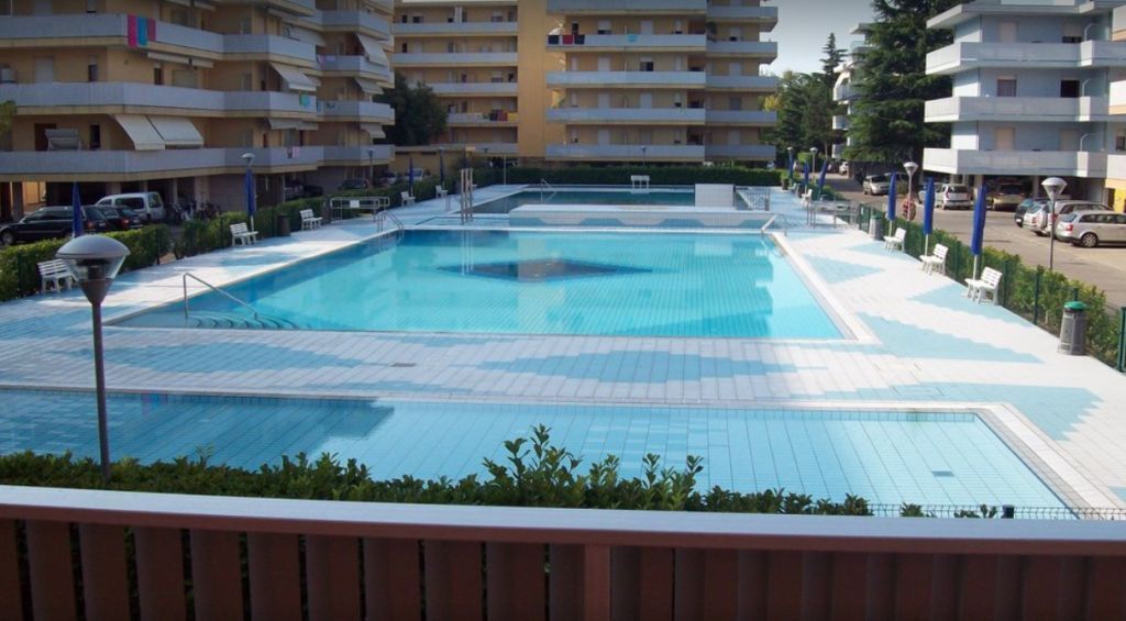 Una piscina circondata da un condominio a più piani con balconi.
