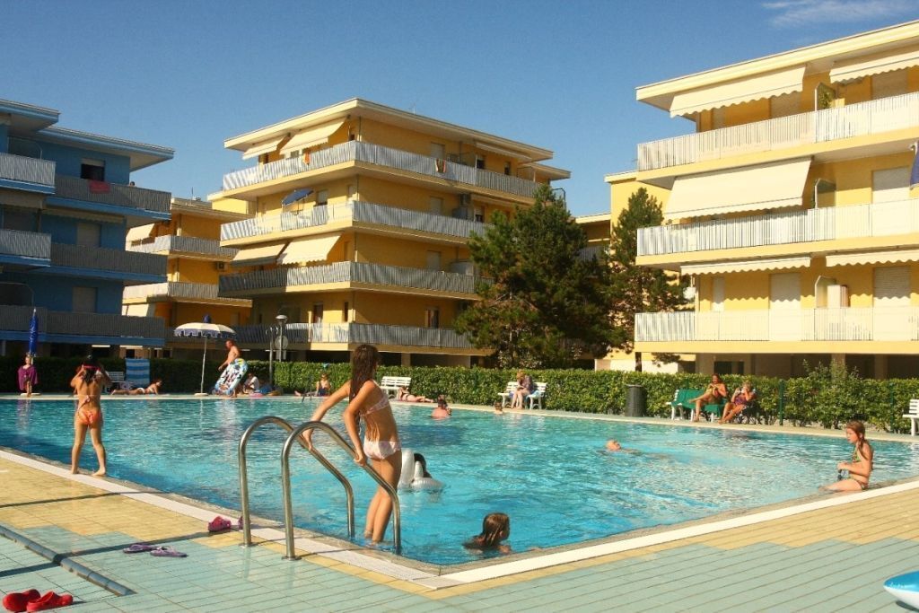 A swimming pool area with multiple balconies and a clear sky.