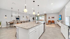 A modern kitchen with a large island, white cabinetry, and pendant lighting. - Last Minute Disney Getaway! Private Pool, Hot Tub & Game Room. Book Now! #42814 (Orlando)