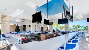 A modern outdoor bar area with multiple seating arrangements, a central bar counter, and a Christmas tree.
