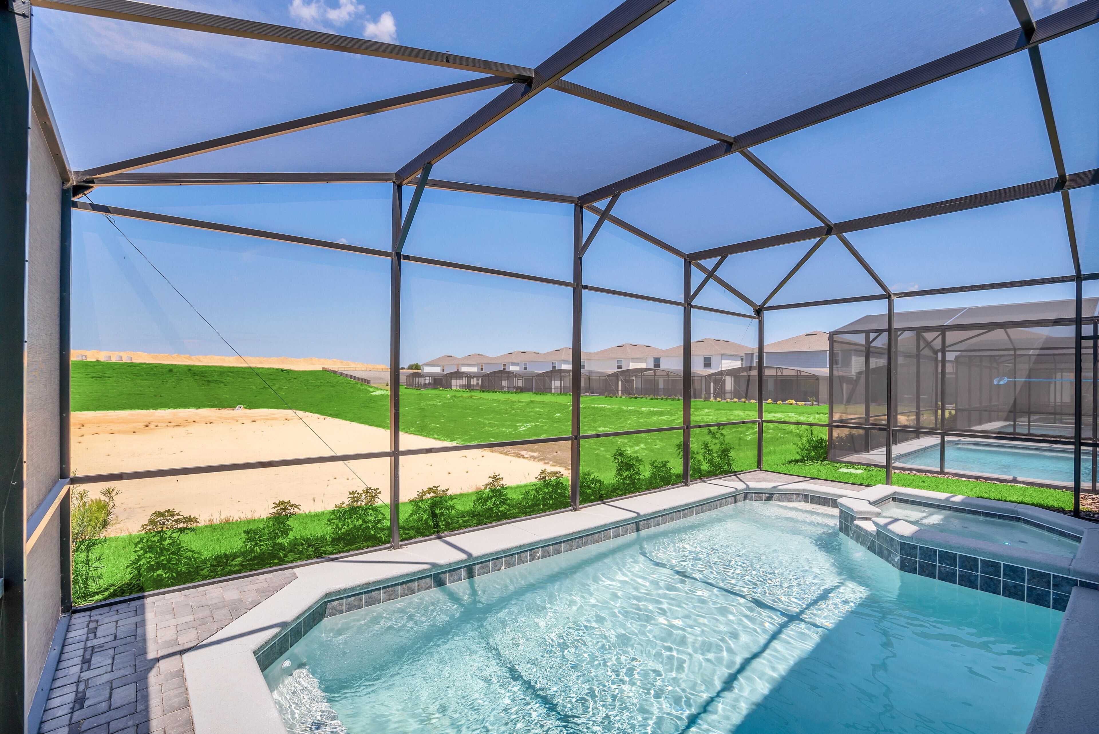 A swimming pool with a clear view of the surrounding landscape, including a grassy area and distant buildings.