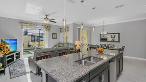 Eine moderne Küche mit Granit-Arbeitsplatten, einer zentralen Kochinsel und einem Essbereich mit einer Kronleuchter.