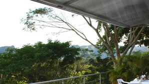 A balcony with a hot tub, white chairs, and a table with bottles.