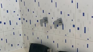 A bathroom with a white sink, two black towel holders, and a tiled wall with a geometric pattern.