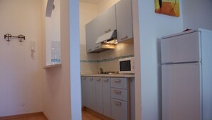 A compact kitchen with light blue cabinets, a microwave, and a refrigerator.
