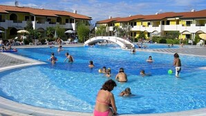 Ein Poolbereich mit mehreren Pools, einer Brücke und Gebäuden mit Balkonen.