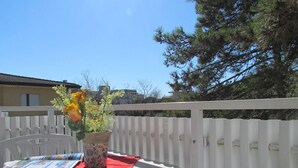 A white balcony with a table, a potted plant, and a red cloth. - Residenz Codan Wohnung Codan für 6 Personen (Bibione)