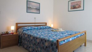 A bedroom with a wooden bed, a nightstand, and two framed pictures on the wall. - Residenz Codan Wohnung Codan für 6 Personen (Bibione)