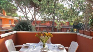 Ein Balkon mit einem Tisch für zwei Personen, umgeben von weißen Stühlen, mit einer Vase voller gelber Blumen in der Mitte.