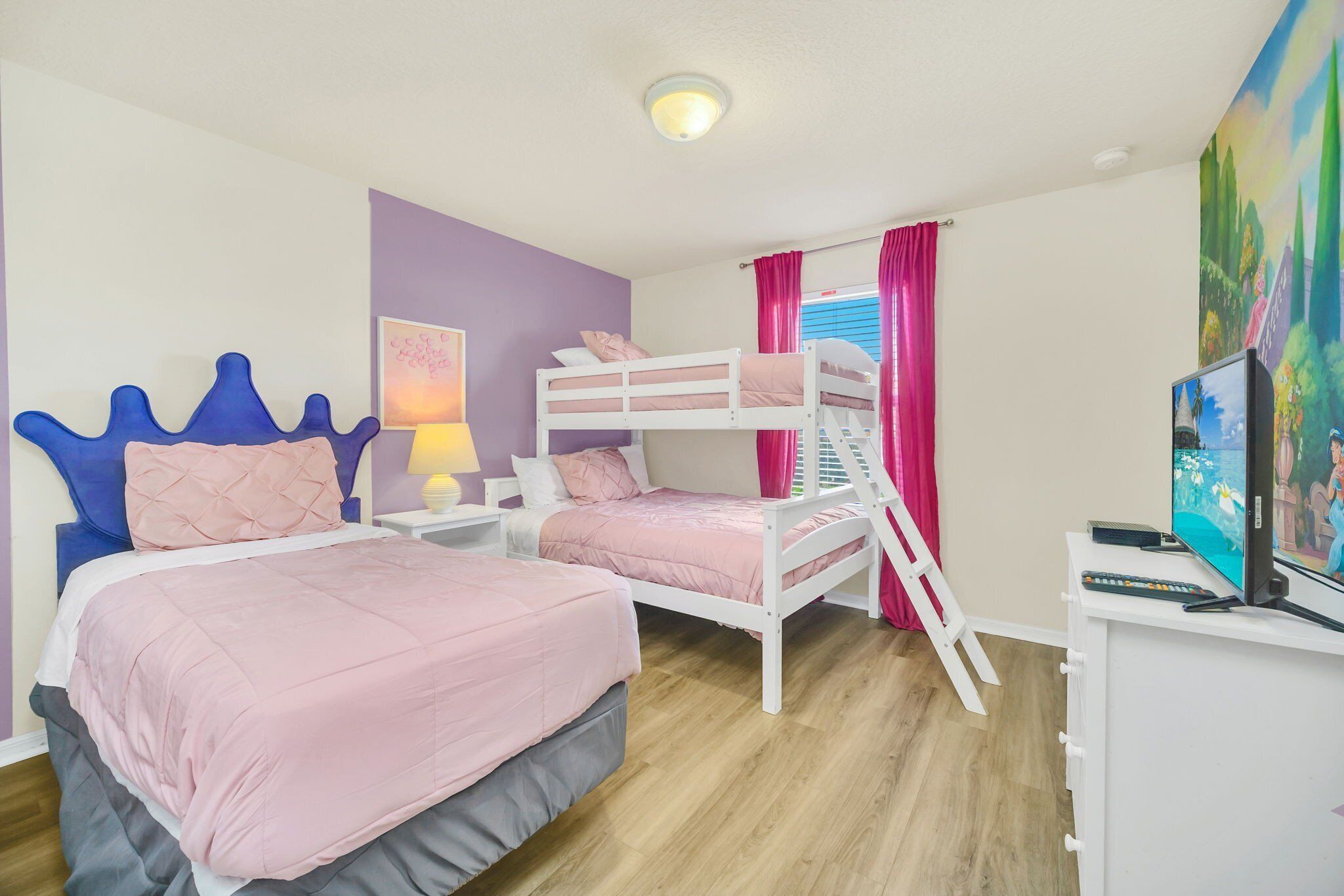 A bedroom with two beds, a bunk bed, a TV, and a painting on the wall.