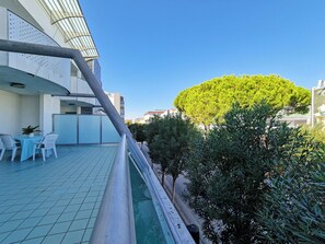 Une cour avec une piscine, un espace salon extérieur et un grand arbre.