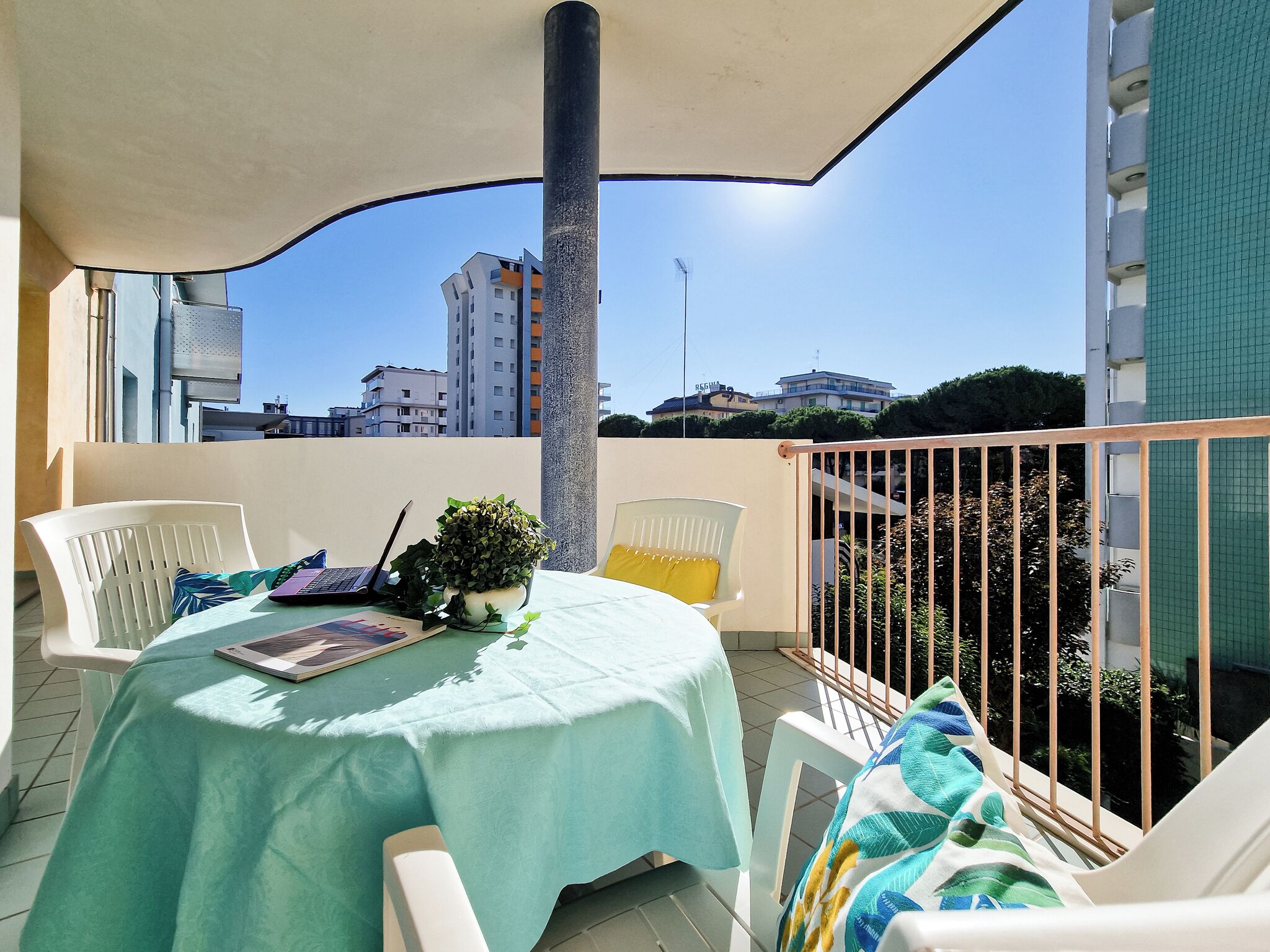 Ein Balkon mit Tisch, Stühlen, einem Laptop und einem Blumentopf.