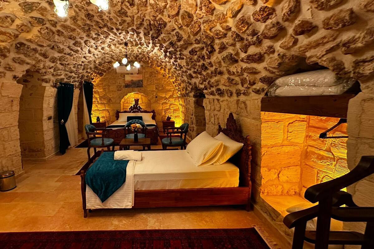 Een kamer met stenen muren, een bed, een bureau en een stoel.