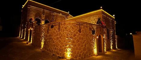 A stone building with a central courtyard, illuminated by warm lighting.