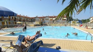 Ein Schwimmbeckenbereich mit Liegestühlen und Sonnenschirmen.