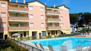 Et hotel med flere etager, en swimmingpool og liggestole.
