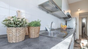 A kitchen with a stainless steel sink, two woven baskets with plants, and a modern backsplash. - Italian Experience - AltoMare Apartment (Porto Sant'elpidio)