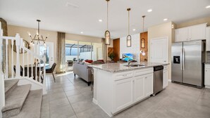 Una cocina moderna con armarios blancos, un refrigerador de acero inoxidable y una isla central con pileta.