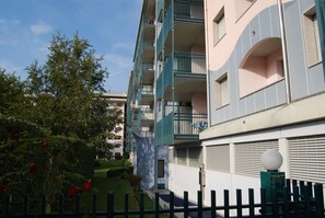 A multi-story residential building with balconies, a gated entrance, and a well-maintained garden.