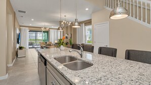 A modern kitchen with granite countertops, stainless steel sinks, and pendant lighting.