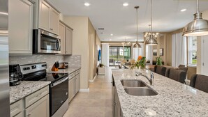 A modern kitchen with granite countertops, stainless steel appliances, and pendant lighting.