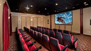 Une salle de conférence avec des rangées de chaises rouges et noires, un grand écran sur lequel est affiché un astronaute en combinaison spatiale, et un tapis à motifs.