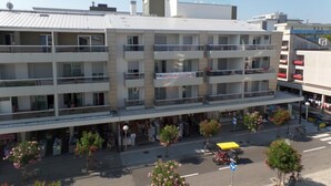 Ein mehrstöckiges Hotel mit Balkonen, ein Erdgeschoss mit Geschäften und ein klarer Himmel.