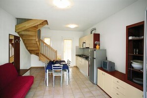 Eine kleine Küche mit einer Holztreppe, einem Essbereich mit einem roten Sofa und einem Fernseher auf der Arbeitsfläche.