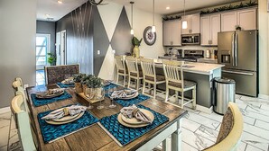 A modern kitchen with a dining area, featuring a central island, stainless steel appliances, and a chandelier. - Last Minute Disney Getaway! Townhouse with Private Pool. Book Now! #87939 (Orlando)