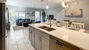 A modern kitchen with a central island, built-in appliances, and a dining area with a view to the living room. - Last Minute Disney Getaway! Townhouse with Private Pool. Book Now! #87939 (Orlando)