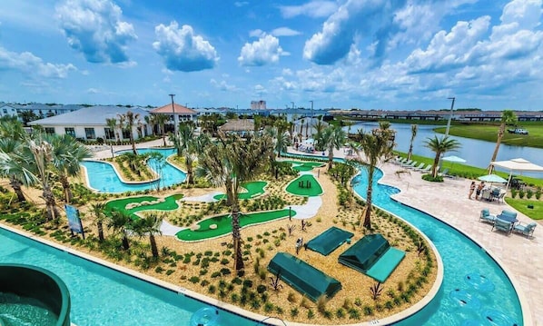 Um resort com várias piscinas, palmeiras e um campo de golfe.