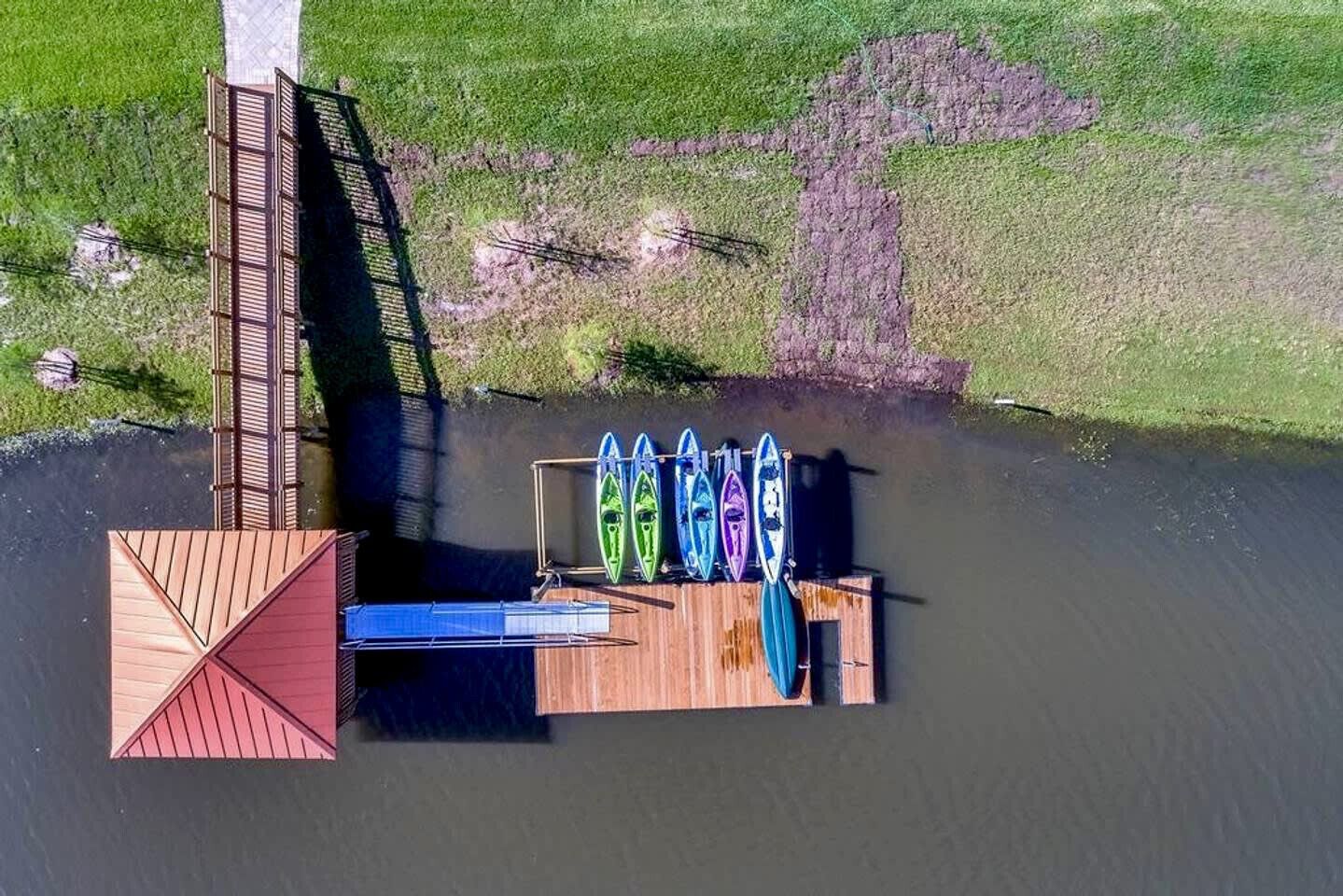 Vue aérienne d’un quai avec des kayaks et une petite structure en bois.