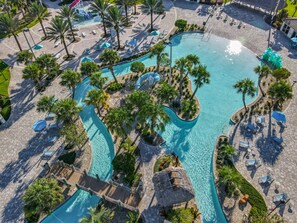 An aerial view of a resort with a large central pool, multiple smaller pools, and numerous sun loungers and umbrellas. - Last Minute Disney Getaway! Townhouse with Private Pool. Book Now! #87961 (Orlando)