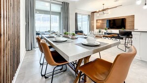 Un comedor moderno con una mesa larga, sillas y una cocina al fondo.