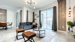 Una sala moderna con un sofá modular, una mesa redonda y un comedor con mesa y sillas.