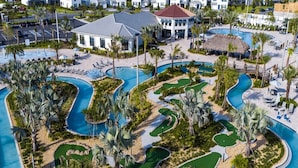 Ein Resort mit großzügiger Poolanlage, Palmen und einem Gebäude mit rotem Dach.