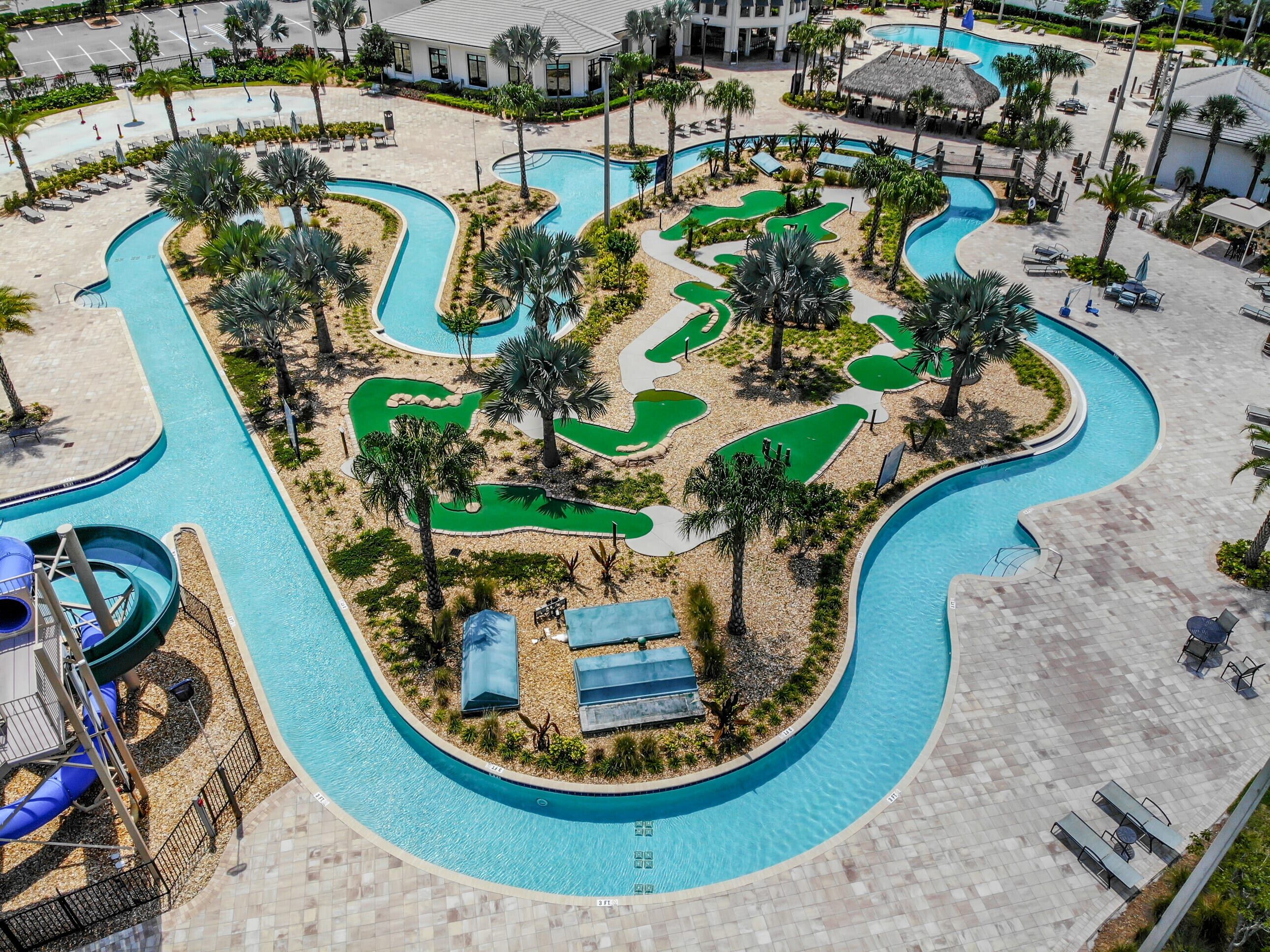 Oversigtsbillede af et resort med en stor swimmingpool, palmer og en golfbane.