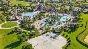 Vista aérea de un resort con varias piscinas, una amplia zona de playa de arena y césped y jardines bien cuidados.