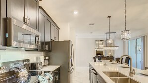 Una cocina moderna con electrodomésticos de acero inoxidable, una isla grande con pileta y una zona de comedor al fondo.