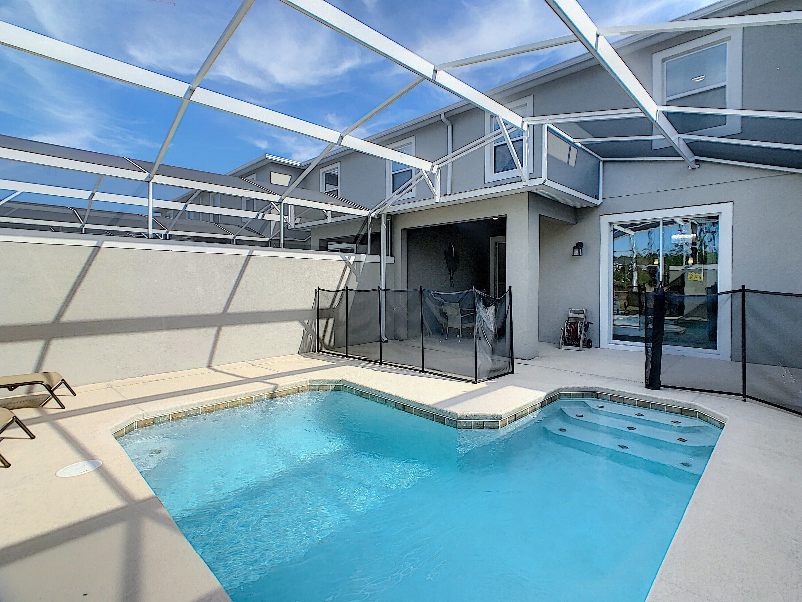 Ein Schwimmbad mit Glasabdeckung, einer überdachten Terrasse und Blick auf den Himmel.