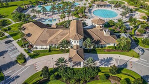 Eine Vogelperspektive zeigt ein Resort mit mehreren Schwimmbecken, einem zentralen Gebäude mit einem Turm und umliegenden Villen.