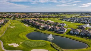 Luftaufnahme eines Golfplatzes mit Teich, Sandbunkern und Wohnhäusern.