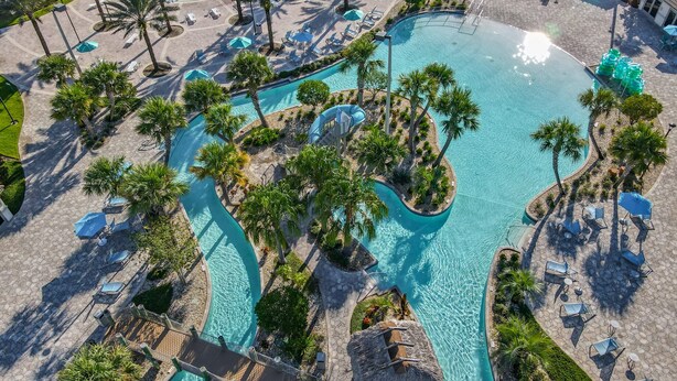 Ein Luftbild eines Resorts mit einem großen zentralen Pool, mehreren kleineren Pools und zahlreichen Liegestühlen und Sonnenschirmen.