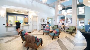 A spacious lobby with wicker chairs, a reception desk, and a fireplace.